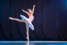 Little Girl Ballerina Is Dancing On Stage In White Tutu On Pointe Shoes Classic Variation.