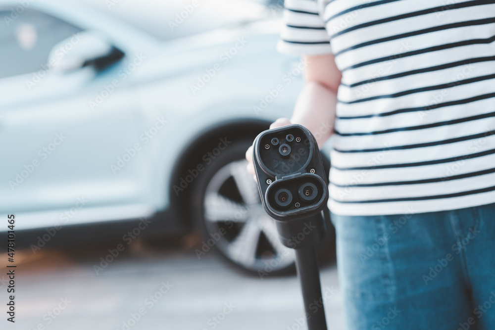 Unrecognizable Asian woman holding a DC - CCS type 2 EV charging ...