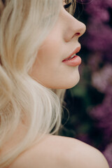 Wall Mural - Young blonde girl near the lilac bushes