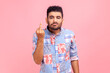 Portrait of irritated young adult man in blue casual style showing middle finger, impolite rude gesture of disrespect, hate and aggression in conflict. Indoor studio shot isolated on pink background.