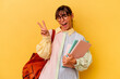 © Asier - Young student Argentinian woman isolated on yellow background joyful and carefree showing a peace symbol with fingers.