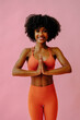 © Carlos David - beautiful African american woman meditating in sports outfit on pink background