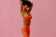 © Carlos David - attractive young black adult woman in sports outfit looking at camera and posing isolated on pink background