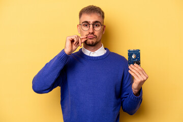 Wall Mural - Young computer man isolated on yellow background with fingers on lips keeping a secret.