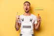 Young painter man isolated on yellow background pointing upside with opened mouth.
