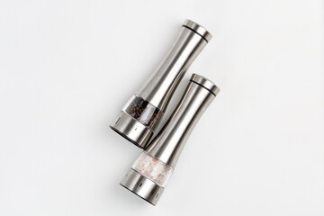 Two electric spice mills for salt and pepper. Metal. On a white table