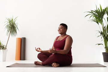 Wall Mural - Positive fat black lady in sportswear having yoga practice