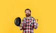 © be free - man holding frying pan.. male chef kitchener cooking. hipster checkered shirt for bearded guy cook. unshaven brutal man with kitchen utensil. household goods. friendly shop assistant