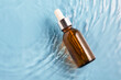 Medical skincare, glass brown serum bottle with collagen on blue water background with waves. beauty product for anti-aging care, moisturizing and cleansing. top view