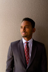 Wall Mural - Portrait of African businessman wearing suit and tie outdoors in city while thinking