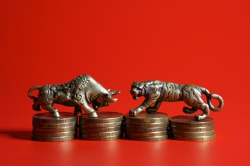 Metal tiger and bull with coins on a red background. Financial symbol. Close-up subjects.