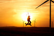 © Jan - Kite land boarder jumps in front of setting sun. 1 man at an extreme sport art in action with a kiteboard. Landscape with wind turbines as silhouette. Side view.