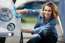 Young Woman Wiping Her Car With Microfiber Cloth