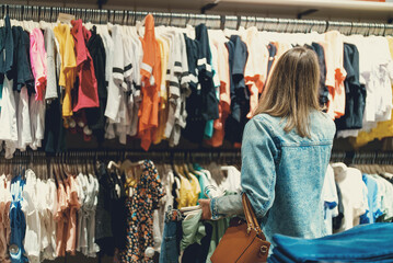 Woman in medical mask choosing clothes in outlet store.