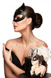 Beautiful woman pastry chef in cat mask and black dress with a cake in her hands.