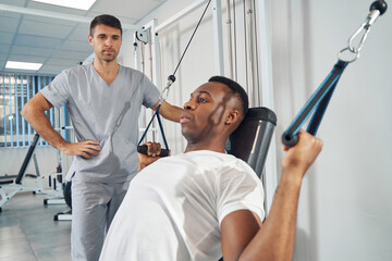 Wall Mural - Man doing strength training exercise using gym equipment