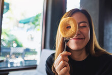 A Funny Young Woman Cover Her Eye And Looking Through Donut