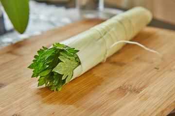 Sticker - Ready-made bouquet of greens lies on a wooden board in the kitchen, for dressing dish