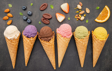 Fototapete - Various of ice cream flavor in cones blueberry ,pistachio ,almond ,orange and chocolate setup on dark stone background . Summer and Sweet menu concept.