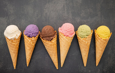 Fototapete - Various of ice cream flavor in cones blueberry ,pistachio ,almond ,orange and chocolate setup on dark stone background . Summer and Sweet menu concept.