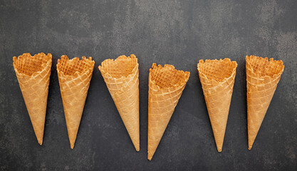 Fototapete - Flat lay ice cream cones collection on dark stone background . Blank crispy ice cream cone with copy space for sweets menu design.
