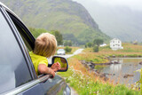 Fototapeta Tulipany - Cute child, peeping out of a window car, looking at a beautiful landcape view in Lofoten