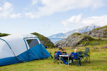 Happy Family With Three Kids, Wild Camping In Norway Summertime, People Having Breakfast Adn Coffee On A Cliff Next To A Fjord