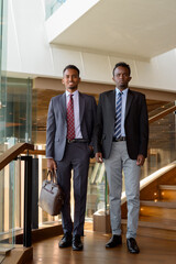 Wall Mural - Two African businessman wearing suit and tie at coffee shop full length shot