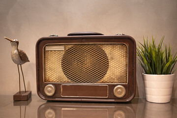 An antique radio with a pot of artificial plant and wooden bird sculpture. Selective focus points