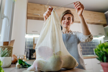 Wall Mural - Young woman tie the organic cotton reusable produce bag with vegetables