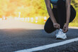 A woman tying her shoes before jogging, she is running in a park where a lot of people come for morning and evening jogging, running is a popular activity. Health care concept with jogging.