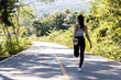 © kamiphotos - An Asian woman warming up before running, she is jogging in a park where many people come for morning and evening jogging, running is another popular activity. Health care concept with jogging.