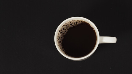 Wall Mural - Hot coffee in white mug isolated on black background. top eye view