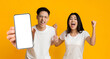 Asian couple showing white empty smartphone screen and gesturing yes