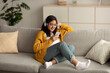 Positive arab lady in wireless headphones listening music on smartphone enjoying new online streaming app