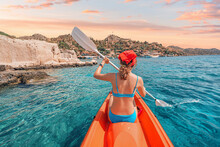 Happy Girl Is Rowing On A Sea Kayak Near Kekova Island With View Of Simena Castle And Kaleucagiz Village In Turkey. Outdoor Recreation And Exploration. Travel As A Lifestyle