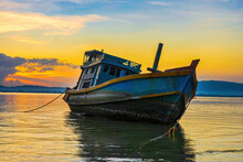 A Fishing Boat Moored At The Shore On A Beautiful Sunrise.