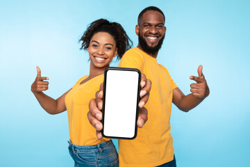 Wall Mural - use this new cool app. positive african american couple pointing at smartphone with blank white scre