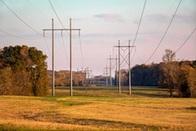 Two Sets Of Tall Overhead Utility Lines Stretch Into The Distance Through Farmland In Rural Northeast Georgia, USA.