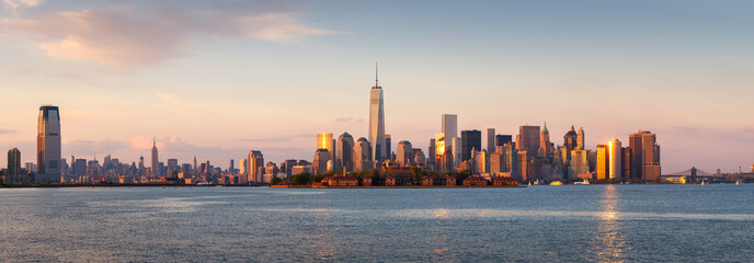Wall Mural - New York City Lower Manhattan skycrapers panoramic view at sunset. Ellis Island in New York Harbor with the World Trade Center