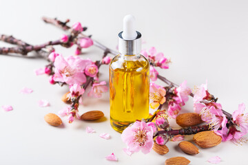 Wall Mural - Almond essential oil in a bottles with spring blossom branches