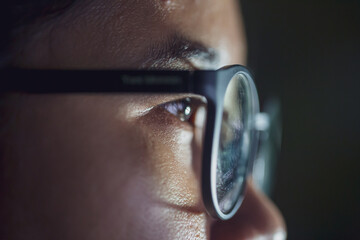 Close up of Young Asian man in glasses watching videos and surfing internet on technology device in the dark 