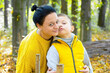 Happy portrait of mother and son hugging in autumn park.
