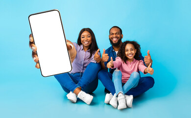 Black family showing empty smartphone screen and thumbs up