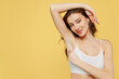 © ViDi Studio - Smiling tender european young brunette woman 20s in white brassiere underwear raise up hand show soft perfect shaved armpit isolated on plain yellow background studio Female beauty bodycare concept.