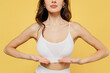 © ViDi Studio - Cropped image of young woman 20s wear white brassiere underwear put hand on chest breast cancer early diagnostic therapy treatment isolated on on plain yellow background studio Augmentation concept
