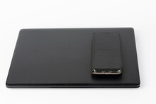 Modern, new office black laptop and touchscreen smarthphone in leather case  on white background