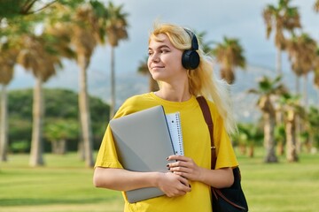 Outdoor portrait of teenage female student with laptop backpack.