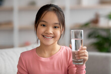 Smiling Little Girl With Glass Of Water At Home