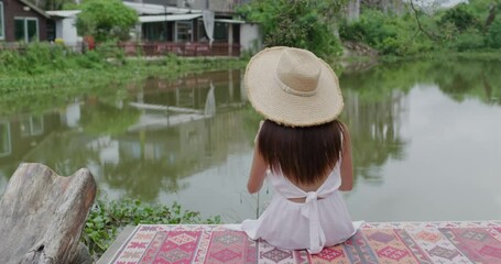 Wall Mural - Woman go out with her dog and sit beside the lake